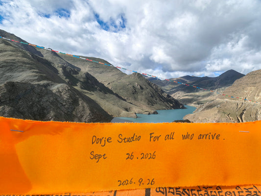 Batch 01 dedication ribbon hand-inscribed "Dorje Studio — For all who arrive", raised Sept 26 2026 at a 4,353 m sacred pass
